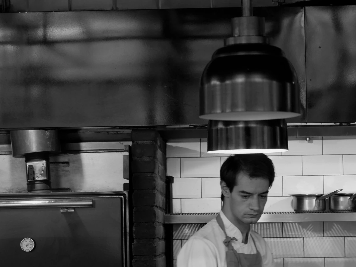 Chef working in a large industrial kitchen surrounded by stainless steel cookware